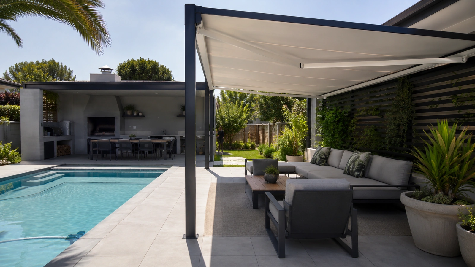 Shade structure over a poolside seating and braai area beside a swimming pool